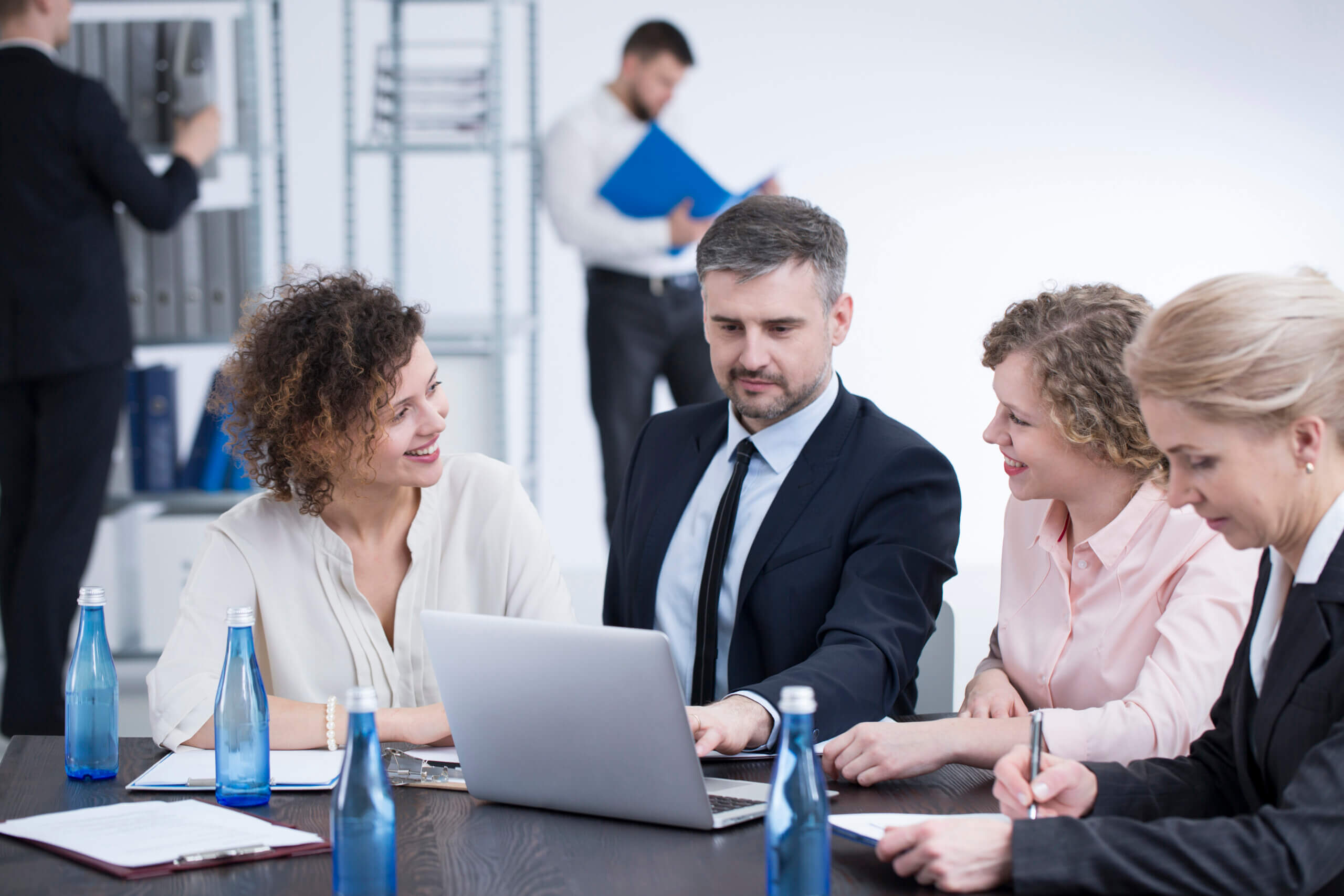 Ein Team von Mitarbeitern, die gemeinsam an einem Laptop arbeiten und eine Präsentation für ein Geschäftstreffen vorbereiten