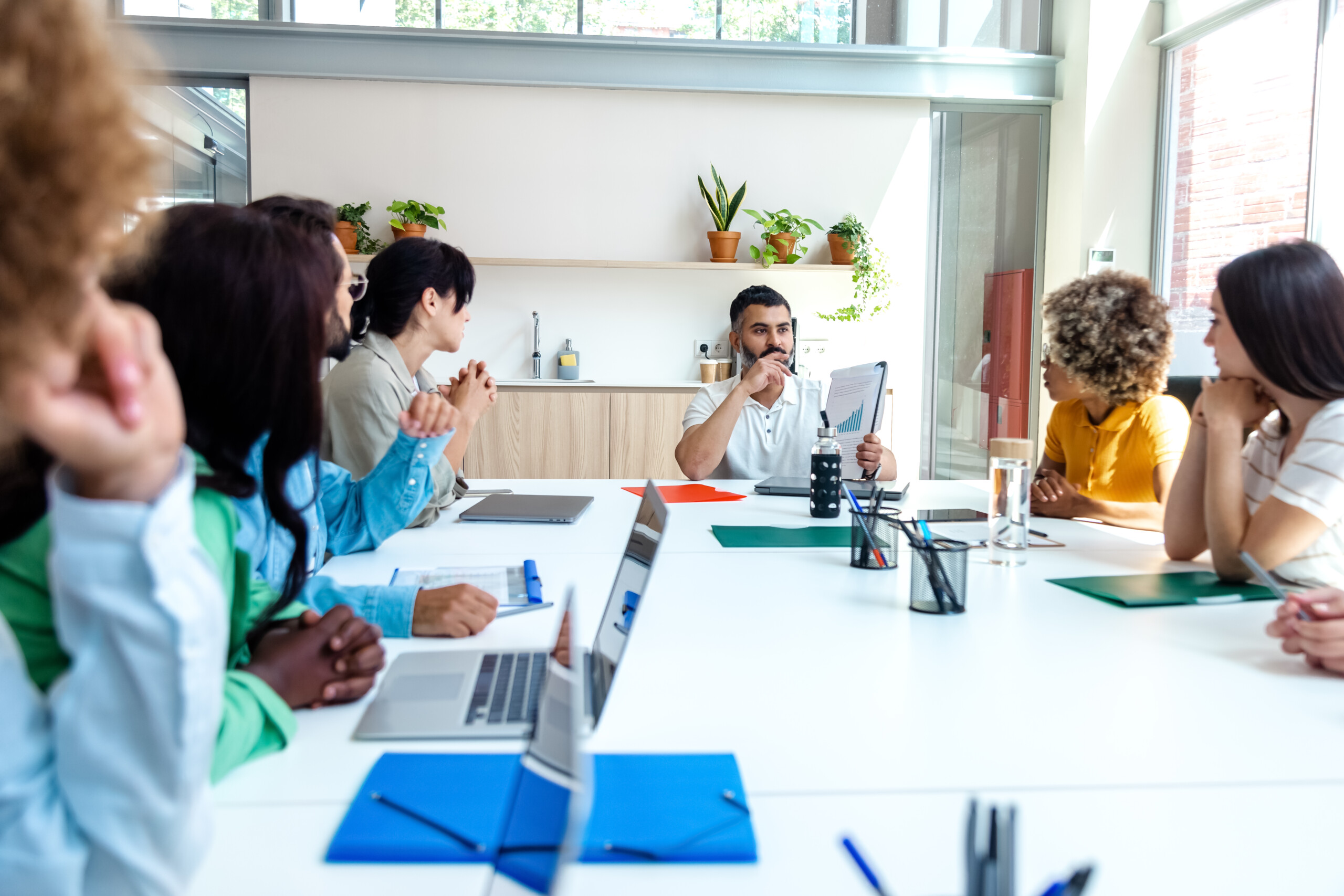 Multiracial employees listen to indian boss in company meeting. Copy space. Händeschütteln nach Mitarbeiter präsentieren mit Mock-up-Kreditkarte Zahlungen an Geschäftskunden. Bereit, Rabatte und Lebensversicherungen anzubieten.